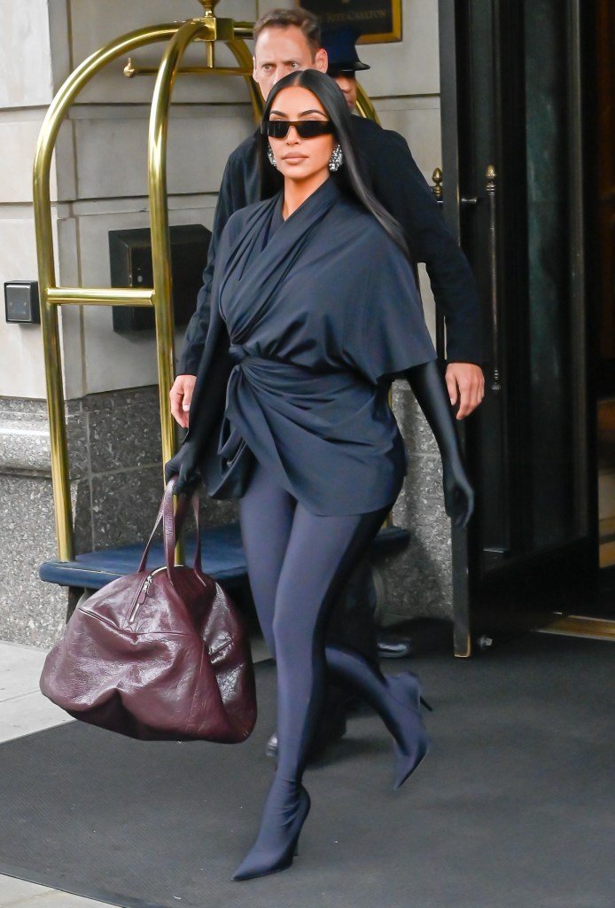 Kim Kardashian walks in Midtown wearing a dark outfit and sunglasses.