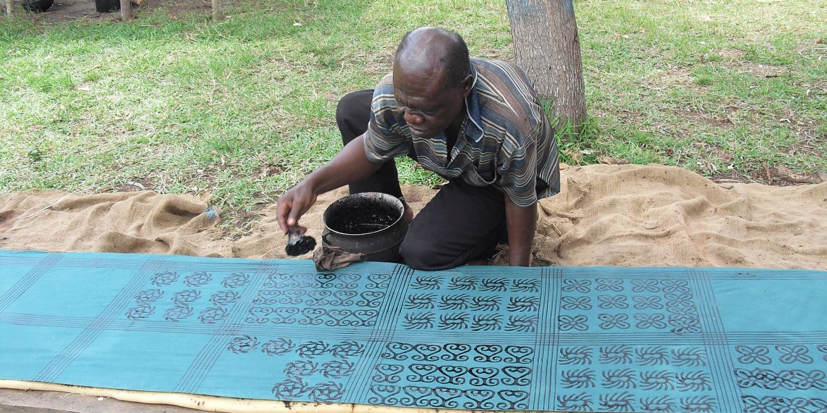 A craftsman printing Adinkra symbols on cloth with natural dye