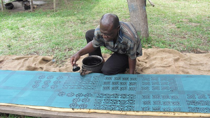 A craftsman printing Adinkra symbols on cloth with natural dye